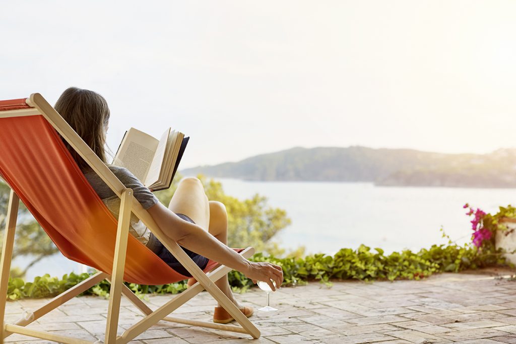 Beneficios del descanso: woman-reading-book-while-relaxing-on-deck-chair