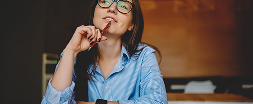 dreamy-woman-podring-while-working-on-journalistic-publication-sitting-with-notebook-in-cafe-thoughtful-female-student-in-eyewear-doing-homework-task-solving-problems-and-analyzing-information