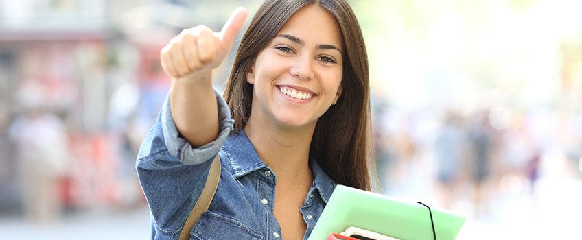 happy-student-posing-with-thumbs-up-in-the-street